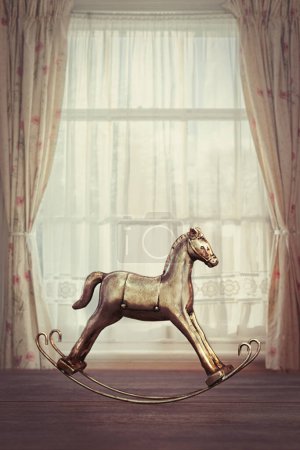 Téléchargez les photos : Jouet à bascule à cheval dans la fenêtre avec rideaux en dentelle - en image libre de droit