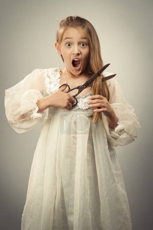 Téléchargez les photos : Image humoristique de jeune fille coupant ses propres cheveux avec de gros ciseaux - en image libre de droit