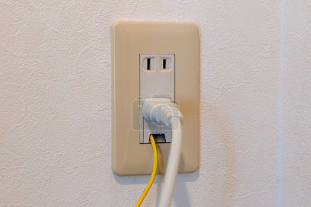 Foto de Power plug and earth wire connected to Japanese electrical outlet on the wall. - Imagen libre de derechos