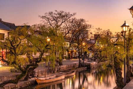 Téléchargez les photos : Préfecture d'Okayama, Japon - 27 déc 2019 : Kurashiki Bikan Historical Quarter in dusk. Paysage urbain connu pour ses murs blancs typiquement japonais de résidences et de saules bordant les rives de la rivière - en image libre de droit