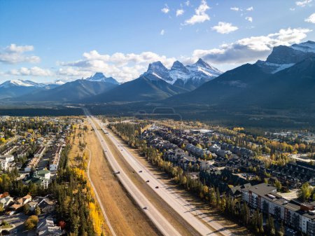 Téléchargez les photos : Canmore, Alberta, Canada. Aerial view of Trans-Canada Highway (Highway 1) in a autumn sunny day. The Three Sisters trio of peaks Canadian Rockies mountain range. - en image libre de droit