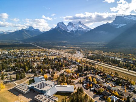 Téléchargez les photos : Canmore, Alberta, Canada. Aerial view of Trans-Canada Highway (Highway 1) in a autumn sunny day. The Three Sisters trio of peaks Canadian Rockies mountain range. - en image libre de droit