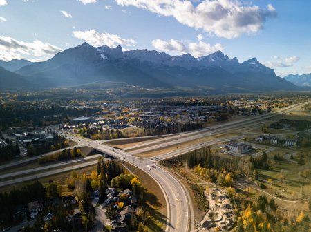 Téléchargez les photos : Aerial view of Trans-Canada Highway (Highway 1) exit 89 to Downtown Canmore in Canadian Rockies in a autumn sunny day. Alberta, Canada. Transportation concept. - en image libre de droit