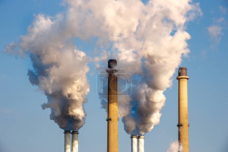 Tubos de chimenea humeantes de una central eléctrica que causan contaminación atmosférica.