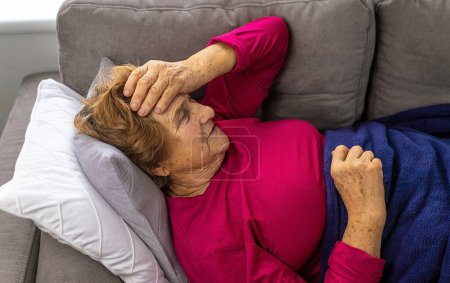 Foto de An old woman lies with a headache. Selective focus. People. - Imagen libre de derechos
