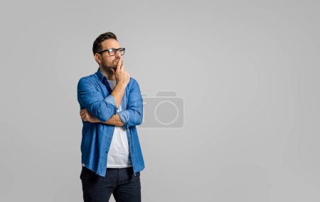 Foto de Joven empresario masculino con la mano en la barbilla ideas de negocios pensando mientras está de pie sobre fondo blanco - Imagen libre de derechos