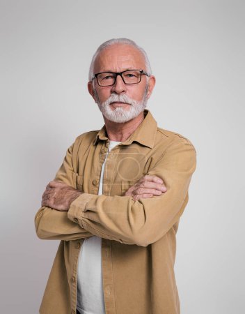 Portrait of confident bearded senior businessman with arms crossed standing on white background