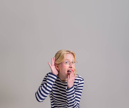 Photo for Excited curious young woman covering her mouth and listening secret on isolated white background - Royalty Free Image