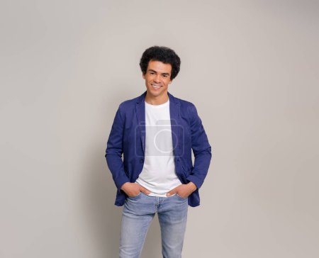 Portrait of confident young salesman with hands in pockets smiling and posing over white background