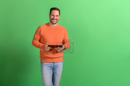 Portrait de sourire beau professionnel vérification des e-mails sur tablette numérique sur fond vert