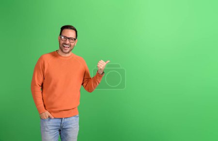 Porträt eines glücklichen Geschäftsmannes, der zur Seite zeigt und auf grünem Hintergrund Werbung für kommerziellen Service macht