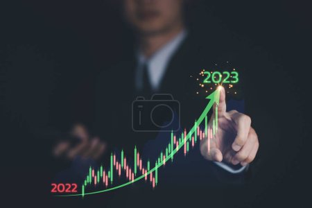 Business growing from 2022 to 2023 year. Businessman hand touch virtual increasing technical graph and up arrow for trader analysis. Stock, Cryptocurrency chart trader, trading, investment, ROI