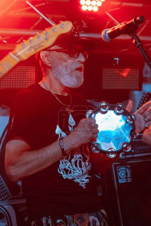 Téléchargez les photos : Vinnytsia, Ukraine - 28.05.2022 : Mykhailo Lundin chanteur et batteur du groupe de rock Braty Hadiukiny joue du tambourin lors du festival Royal Pub, effet flou à faible luminosité, bruit élevé - en image libre de droit
