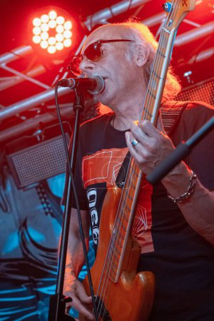 Téléchargez les photos : Vinnytsia, Ukraine - 28.05.2022 : Ihor Melnychuk chanteur et bassiste du groupe de rock Braty Hadiukiny jouent émotionnellement sur la scène du Royal Pub, performance de festival live, motion blur, bruit élevé - en image libre de droit
