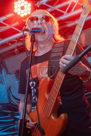 Foto de Vinnytsia, Ucrania - 28.05.2022: Ihor Melnychuk toca Fender bass y canta en Shure mic, vocalista y bajista de Braty Hadiukiny grupo de rock en Royal Pub escenario, festival en vivo, desenfoque de movimiento, alto ruido - Imagen libre de derechos