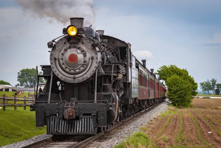 Photo for View of a Restored Steam Train Approaching Head-On Blowing Smoke and Steam on a Spring Day - Royalty Free Image