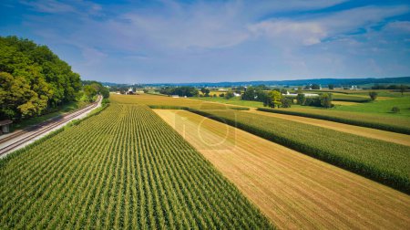 Drone View of Amish Countryside With Barns and Silos and a Single Railroad Track Traveling Through It, on Sunny Day.