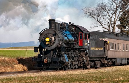 Téléchargez les photos : Ronks, Pennsylvania, December 28, 2022 - A View of a Classic Steam Passenger Train Approaching, Traveling Thru the Countryside, Blowing Smoke and Steam on a Winter Day - en image libre de droit