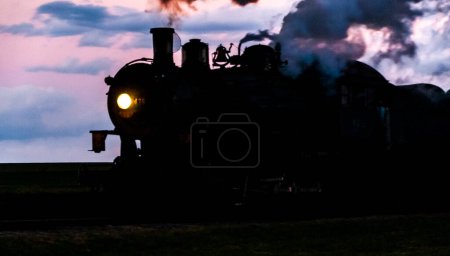 Foto de A Silhouette of a Classic Steam Engine Blowing Smoke and Steam - Imagen libre de derechos