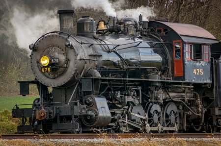Foto de Ronks, Pennsylvania, December 3, 2022 - A View of a Classic Steam Passenger Train, Blowing Lots of Smoke and Steam, While Traveling in the Countryside on an Autumn Day - Imagen libre de derechos