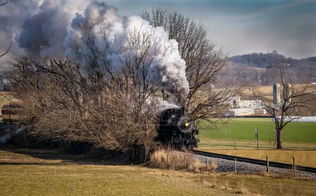 Foto de A View of a Classic Steam Passenger Train Approaching, Traveling Thru the Countryside, Blowing Smoke and Steam on a Winter Day - Imagen libre de derechos