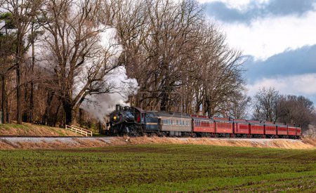 Foto de Ronks, Pennsylvania, December 3, 2022 - A View of a Classic Steam Passenger Train, Blowing Lots of Smoke and Steam, While Traveling in the Countryside on an Autumn Day - Imagen libre de derechos