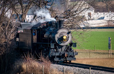 Foto de Ronks, Pennsylvania, December 30, 2022 - A View of a Classic Steam Passenger Train Approaching, Traveling Thru the Countryside, Blowing Smoke and Steam on a Winter Day - Imagen libre de derechos