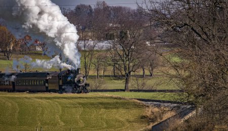 Téléchargez les photos : A View of An Antique Passenger Train Approaching, Blowing Smoke and Steam, on an Autumn Day - en image libre de droit