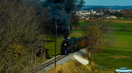 Photo for An Aerial View of a Streamlined Steam Passenger Train Traveling Thru Fertile Farmlands Blowing Black Smoke on an Autumn Day - Royalty Free Image