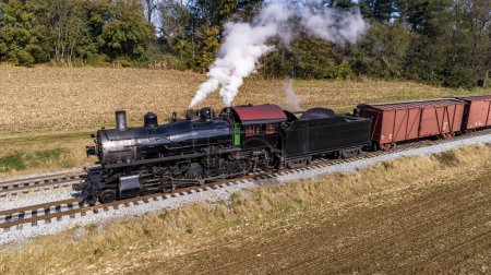 Photo for An Aerial View of an Antique Steam Freight Passenger Train Blowing Smoke as it Slowly Travels on an Autumn Day - Royalty Free Image