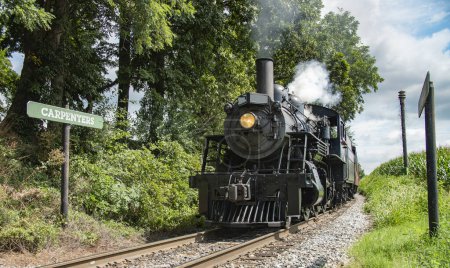 Photo for Historic Number 89 Steam Train Approaching Carpenters Station Amid Lush Trees On A Clear Day. - Royalty Free Image