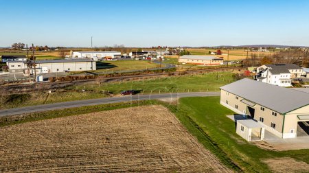 Cette image contraste magnifiquement les bâtiments industriels avec un paysage rural automnal environnant, parfait pour illustrer le développement industriel rural.