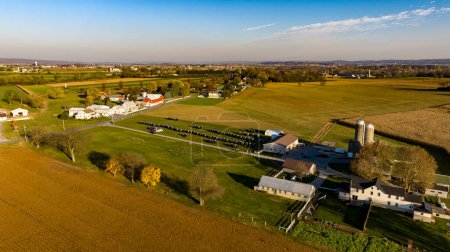 Esta imagen aérea muestra la vasta belleza de las tierras de cultivo Amish al atardecer, con un sereno telón de fondo al atardecer, destacando la armoniosa mezcla de las comunidades con la naturaleza. para una boda amish