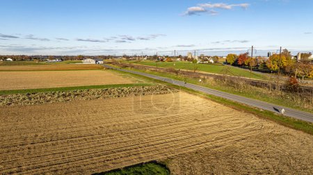 Une vue aérienne sereine saisit l'heure dorée sur divers champs de cultures, avec de longues ombres accentuant les riches textures des terres agricoles.