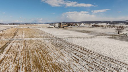 Eine Luftaufnahme von schneebedeckten landwirtschaftlichen Feldern und landwirtschaftlichen Gebäuden.