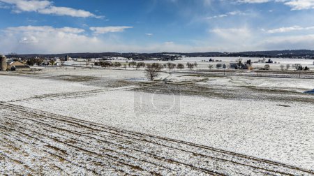 Foto de Una vista aérea de campos agrícolas con motas de nieve y edificios de granjas. - Imagen libre de derechos