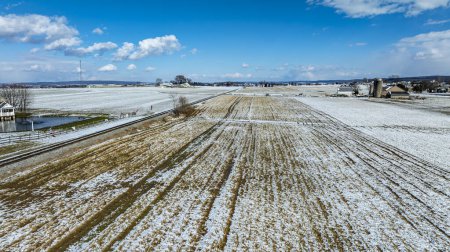An Aerial View Of Snow-Dusted Farm Fields With A Railroad And Silos.