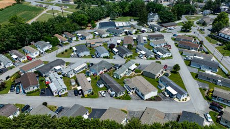 Overhead aerial view of a suburban Mobile, Prefab, Manufactured, neighborhood park, featuring rows of homes, neatly trimmed lawns, and parked cars