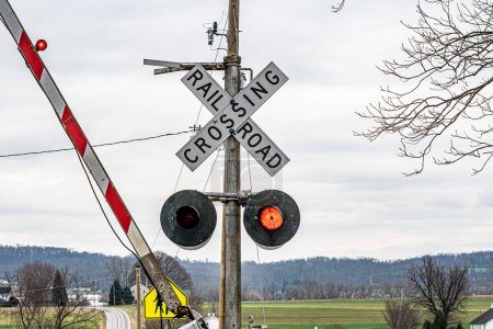 A railroad crossing sign is on a pole. The sign is red and white