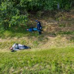Ronks, Pennsylvania, USA, June 8, 2024 - Civil War Reenactors In Blue And Gray Uniforms Lie On The Grass, Portraying A Battle Scene With Fallen Soldiers Near A Wooded Area, With One Standing Guard