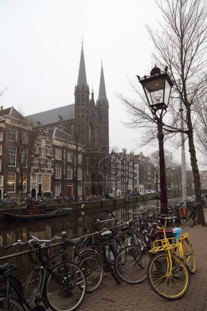 Photo for Amsterdam, The Netherlands - December 15, 2016: Canal with parked bicycles and a church in Amsterdam, The Netherlands on December 15, 2016 - Royalty Free Image