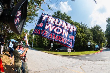 Foto de Atlanta, GA / USA - 24 de agosto de 2023: Una bandera que dice "Trump ganó. Save America "vuela mientras la gente se reúne a la espera del arresto de Donald Trump en la cárcel del condado de Fulton el 24 de agosto de 2023 en Atlanta, GA. - Imagen libre de derechos