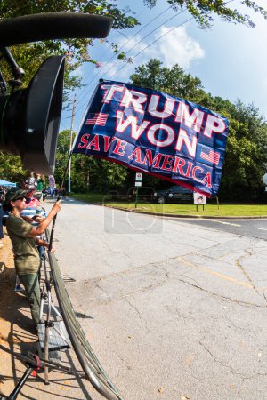 Photo for Atlanta, GA / USA - August 24, 2023:  A flag that says "Trump Won. Save America" flies while people gather awaiting Donald Trump's arrest at the Fulton County Jail on August 24, 2023 in Atlanta, GA. - Royalty Free Image