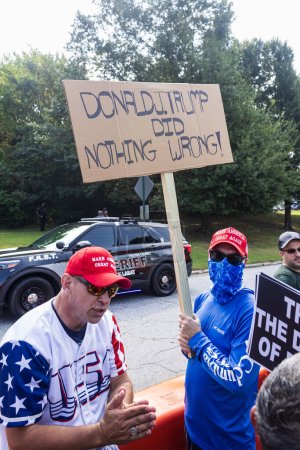 Foto de Atlanta, GA / Estados Unidos - 24 de agosto de 2023: Un hombre sostiene un letrero hecho a mano que dice "Donald J. Trump no hizo nada malo" mientras esperaba el arresto de Trump en la cárcel del condado de Fulton el 24 de agosto de 2023 en Atlanta, GA. - Imagen libre de derechos