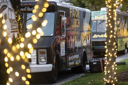 Téléchargez les photos : Suwanee, GA / USA - Le 4 août 2023 : Deux camions de nourriture sont stationnés parmi de jolies lumières dorées au Food Truck Vendredi, 4 Août, 2023 à Suwanee, GA. - en image libre de droit