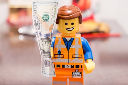 Foto de Slovakia. Sala. 01/01/2023. Banknote in the hands of a LEGO worker, with a joyful expression on his face.. Money in the hands of Lego Movie 2 Emmet Smile. - Imagen libre de derechos