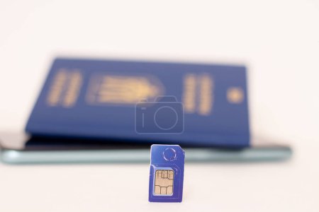 Photo for Sim card on the background of a mobile phone and a passport of Ukraine. - Royalty Free Image