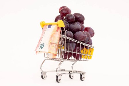 Photo for Red grapes with 10 euro in a grocery basket. On a white background. - Royalty Free Image