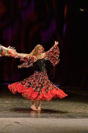 Photo for A girl in a national dress dances a gypsy dance on stage - Royalty Free Image