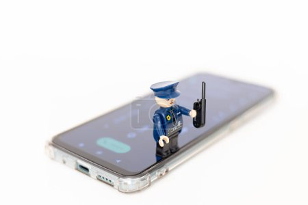 Téléchargez les photos : Un policier jouet sur un téléphone portable. Protection des données personnelles des utilisateurs. Lutte contre la cybercriminalité - en image libre de droit